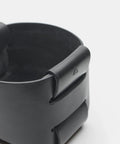 Gros plan sur le pli emboîté et le logo du panier en cuir noir