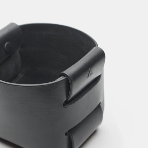 Gros plan sur le pli emboîté et le logo du panier en cuir noir