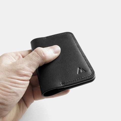 Porte-cartes cuir noir dans la main montrant taille compacte minimaliste