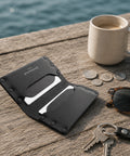 Porte-cartes cuir noir sur un ponton avec café et clés