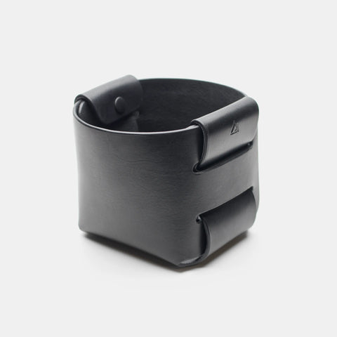 Panier vide-poche en cuir noir vu de trois quarts, avec intérieur non doublé visible