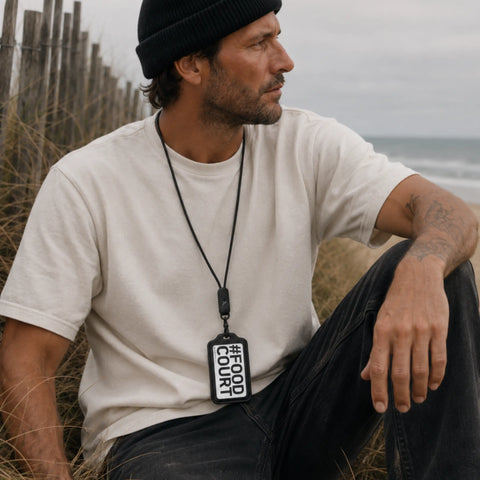 Porte-badge cuir noir pour homme porté assis sur les dunes