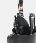 Gros plan sur pot à crayons cuir fait main avec stylos et pinceaux