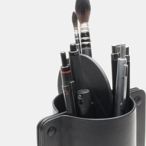 Gros plan sur pot à crayons cuir fait main avec stylos et pinceaux