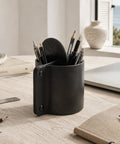 Pot à crayons en cuir noir avec crayons sur un bureau en bois