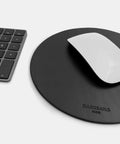 Round mousepad in black leather shown in desk workspace setup