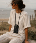 Femme portant l'étui téléphone tour de cou en cuir noir à la plage